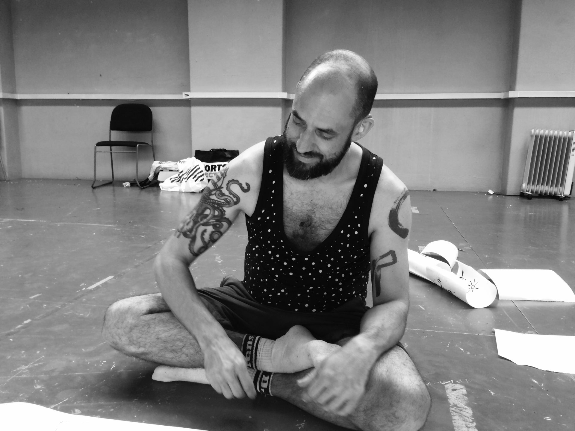 Jonny sits happily cross legged on the floor looking at some paper he's about to draw on